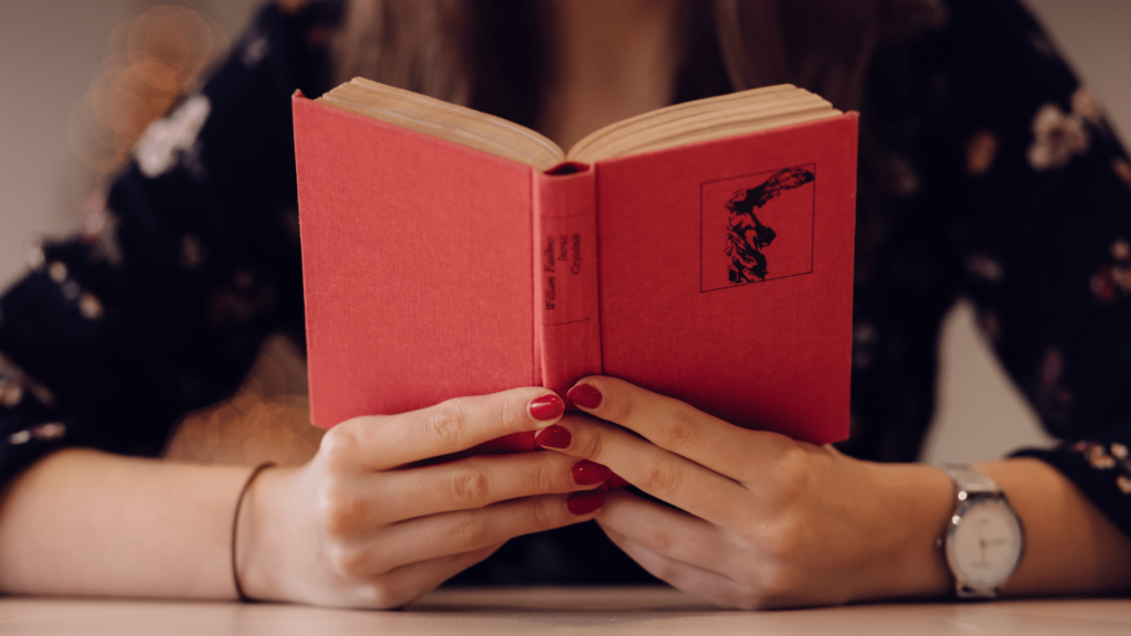 Close-up photo of woman's hands holding a book while reading.